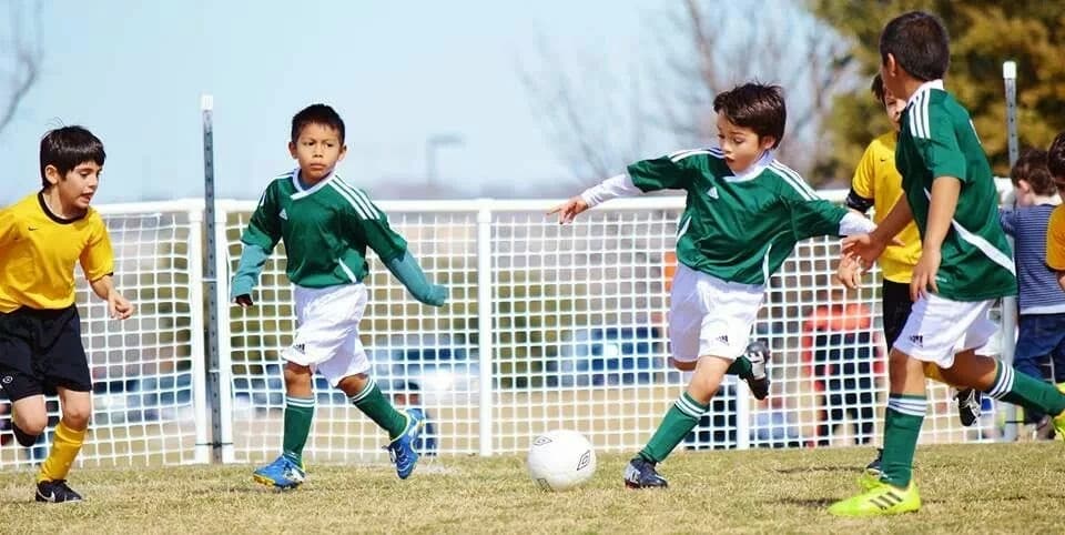 FC Leones youth players in green and white competing for the ball during a match